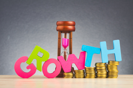 Business success concept, stacking coins and word GROWTH on wooden desk over beautiful reverberation gradient backgroundの写真素材