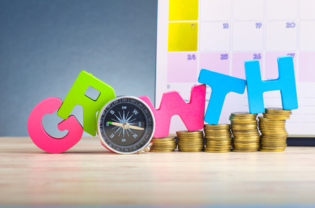 Business success concept, stacking coins and word GROWTH on wooden desk over beautiful reverberation gradient backgroundの写真素材