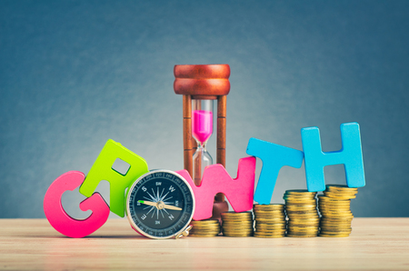 Business success concept, stacking coins and word GROWTH on wooden desk over beautiful reverberation gradient backgroundの写真素材