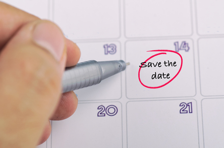 Time planning concept,  cropped hand and yellow sticky paper with word SAVE THE DATE on calendarの写真素材