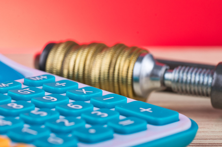 devaluation and financial crisis, calculator and coins squeezed tightly in a G-Clampの写真素材