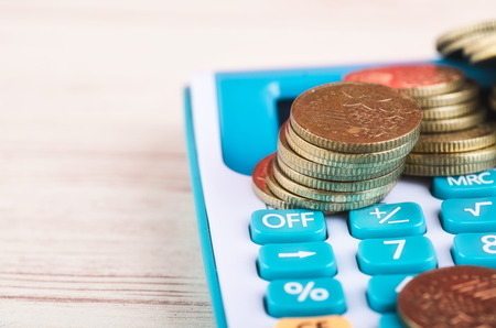 Stacking coins on calculator over wooden background for saving business investment conceptの写真素材