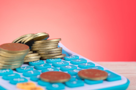 Stacking coins on calculator over beautiful reverberation gradient background for saving business investment conceptの写真素材
