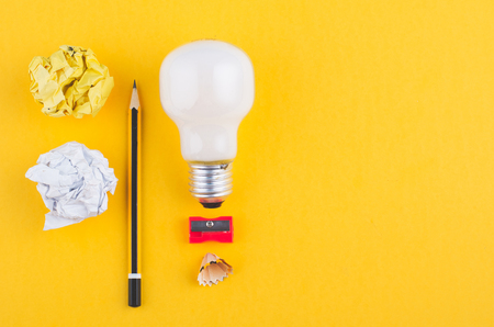 pencil, crumple paper and bulb over yellow background for creative ideas conceptの写真素材