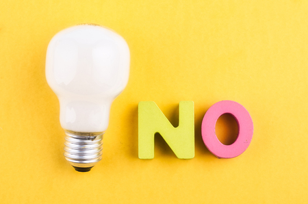 word NO and light bulb on yellow backgroundの写真素材