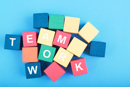 TEAMWORK word on wooden cube over blue background for cooperation, togetherness or partnership conceptの写真素材
