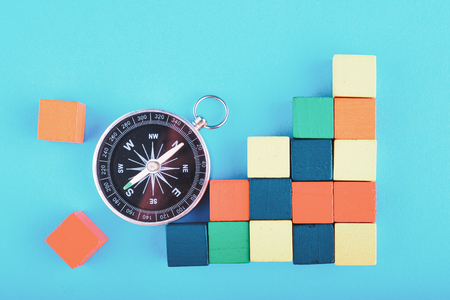 compass and colorful wooden cube on blue background for travel or direction conceptの写真素材