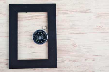 top view empty photo frame and compass on wooden backgroundの写真素材