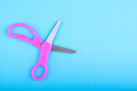 top view of a pair of purple scissor on blue background.copy space for textの写真素材