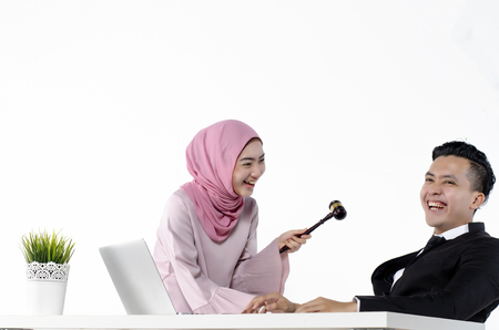 studio portrait of young hijab muslimah joking with her officemate, funny and happy momentの写真素材