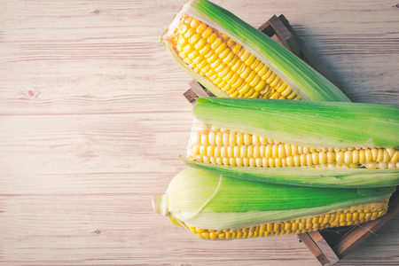 fresh raw sweet corn on the cob kernels over wooden backgroundの写真素材