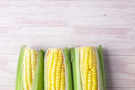 fresh raw sweet corn on the cob kernels over wooden backgroundの写真素材