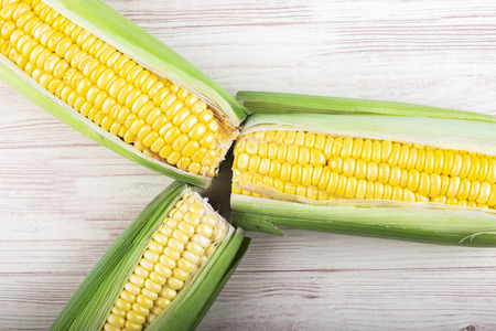 fresh raw sweet corn on the cob kernels over wooden backgroundの写真素材