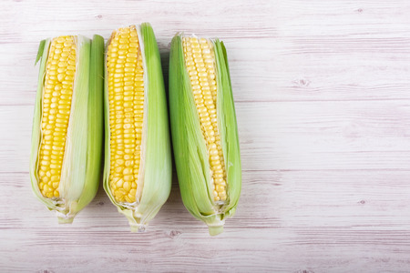 fresh raw sweet corn on the cob kernels over wooden backgroundの写真素材