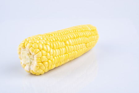 fresh raw sweet corn on the cob kernels over white backgroundの写真素材