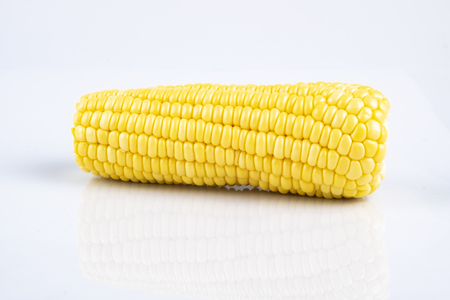 fresh raw sweet corn on the cob kernels over white backgroundの写真素材