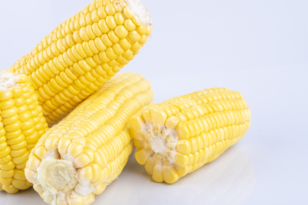 fresh raw sweet corn on the cob kernels over white backgroundの写真素材