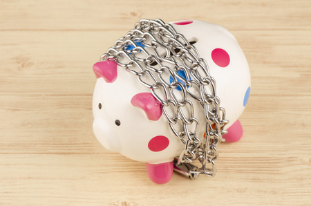financial crisis or economic depression concept, piggy bank surrounded by chains  and padlock on wooden deskの写真素材