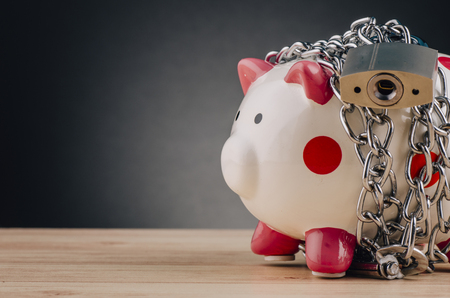 financial crisis or economic depression concept, piggy bank surrounded by chains  and padlock on wooden deskの写真素材