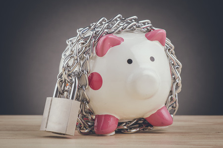 financial crisis or economic depression concept, piggy bank surrounded by chains  and padlock on wooden deskの写真素材
