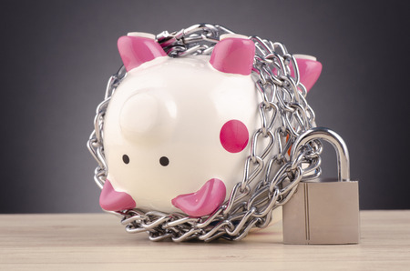 financial crisis or economic depression concept, piggy bank surrounded by chains  and padlock on wooden deskの写真素材