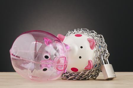financial crisis or economic depression concept, piggy bank surrounded by chains  and padlock on wooden deskの写真素材