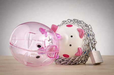 financial crisis or economic depression concept, piggy bank surrounded by chains  and padlock on wooden deskの写真素材