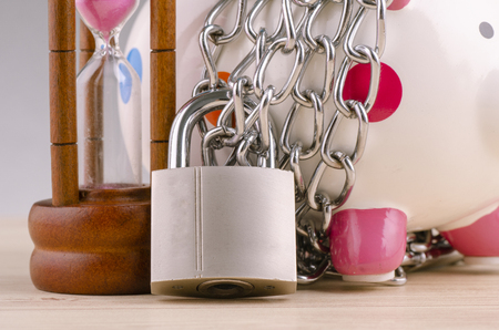 financial crisis or economic depression concept, piggy bank surrounded by chains  and padlock on wooden deskの写真素材