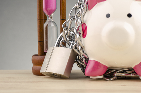 financial crisis or economic depression concept, piggy bank surrounded by chains  and padlock on wooden deskの写真素材