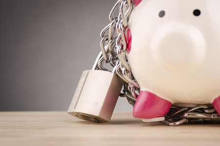 financial crisis or economic depression concept, piggy bank surrounded by chains  and padlock on wooden deskの写真素材
