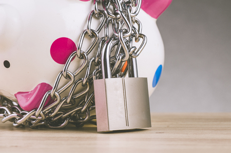 financial crisis or economic depression concept, piggy bank surrounded by chains  and padlock on wooden deskの写真素材