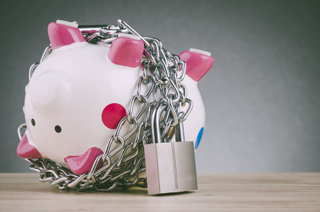 financial crisis or economic depression concept, piggy bank surrounded by chains  and padlock on wooden deskの写真素材