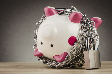 financial crisis or economic depression concept, piggy bank surrounded by chains  and padlock on wooden deskの写真素材