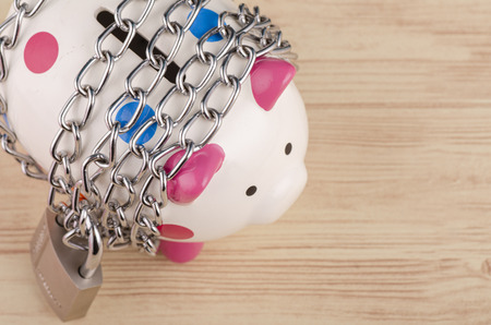 financial crisis or economic depression concept, piggy bank surrounded by chains  and padlock on wooden deskの写真素材