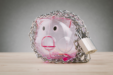 financial crisis or economic depression concept, piggy bank surrounded by chains  and padlock on wooden deskの写真素材