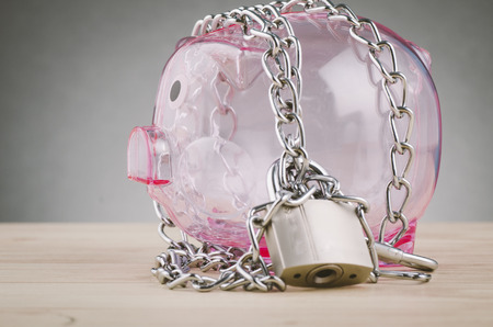 financial crisis or economic depression concept, piggy bank surrounded by chains  and padlock on wooden deskの写真素材