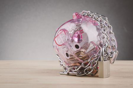 financial crisis or economic depression concept, piggy bank surrounded by chains  and padlock on wooden deskの写真素材