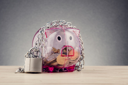 financial crisis or economic depression concept, piggy bank surrounded by chains  and padlock on wooden deskの写真素材