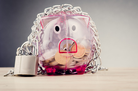 financial crisis or economic depression concept, piggy bank surrounded by chains  and padlock on wooden deskの写真素材