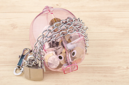 financial crisis or economic depression concept, piggy bank surrounded by chains  and padlock on wooden deskの写真素材