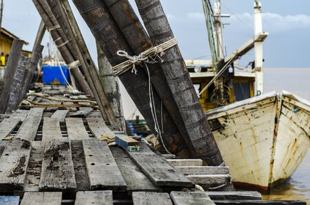 Beautiful rural scenery, fisherman boat moored near wooden jetty over cloudy sky background