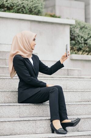 Portrait of young Businesswoman in black suit using a mobile phone for a video call with partners or selfieの写真素材