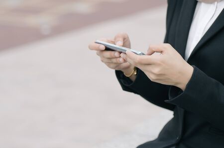 unidentified businesswoman in elegant suit sitting holding mobile phoneの写真素材