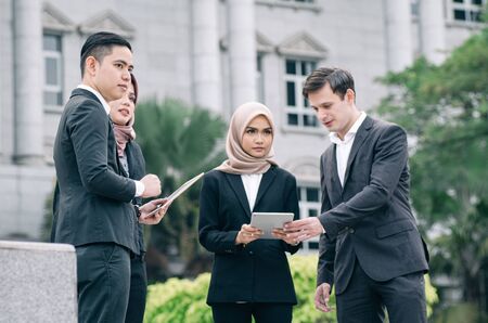 Group of young executive people in formalwear discussing something and gesturingの写真素材