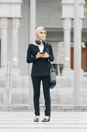 Portrait of young Office Woman Texting to Someone on her Mobile Phone with Happy Facial Expression.の写真素材