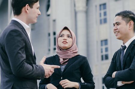 Group of young executive people in formalwear discussing something and gesturingの写真素材