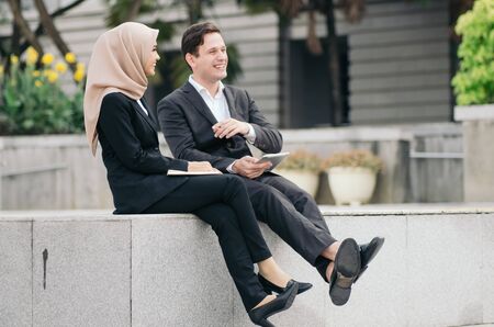 Portrait of young couple in formalwear sitting with happy and cheerful face expressionの写真素材
