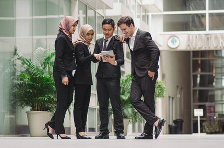 Group of young executive people in formalwear holding tablet and discussing something.の写真素材