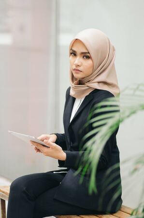 unhappy young business woman sitting and look at her mobile tablet