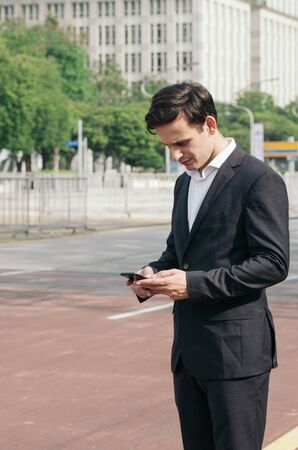 Portrait of young businessman Texting to Someone on his Mobile Phone with Happy Facial Expression.の写真素材